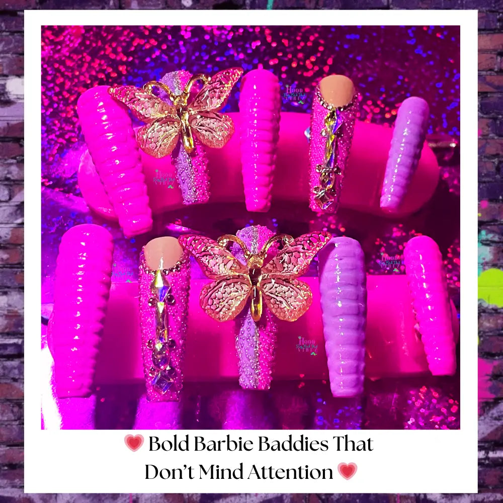 “Hot pink and lavender Barbie Bitch press-on nails with gold butterfly charms, glitter accents, and ribbed 3D texture displayed on pink stands.”