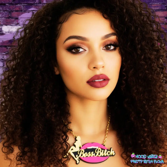 Model wearing Boss Bitch statement necklace featuring gold script lettering layered over glossy pink lips with a gold-tone chain.