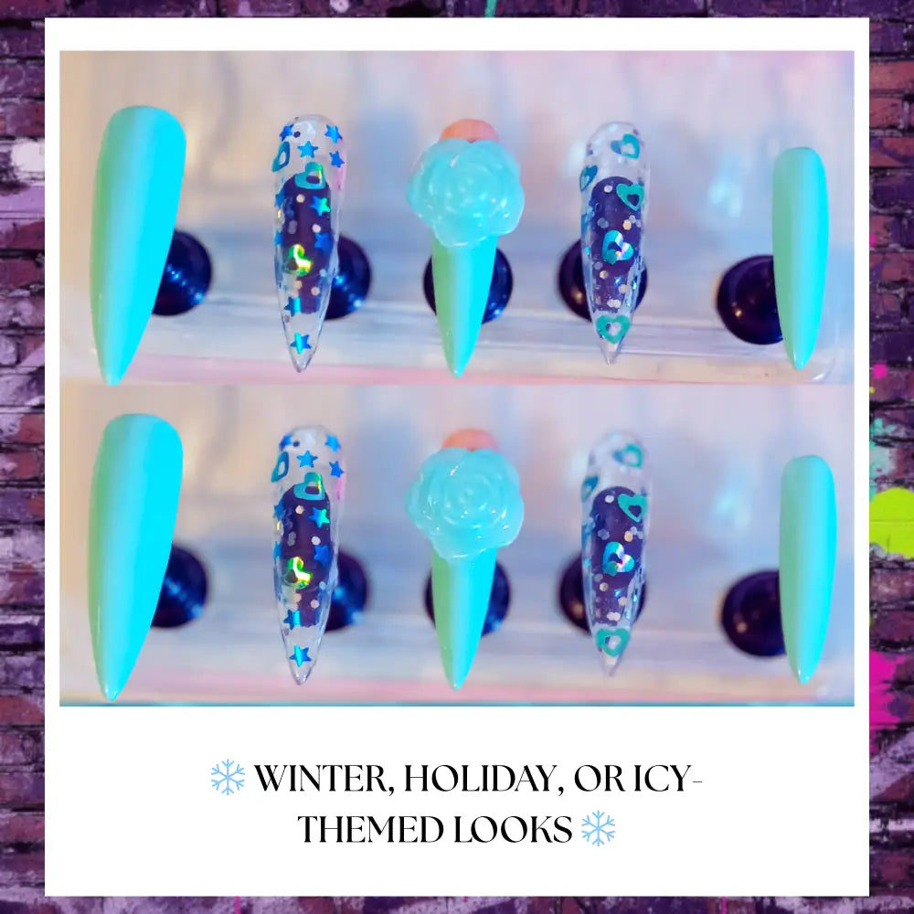 “Icy blue press on nails with glitter finish, 3D rose charms, and crystal accents arranged on clear stands against a blue frosted background.”
