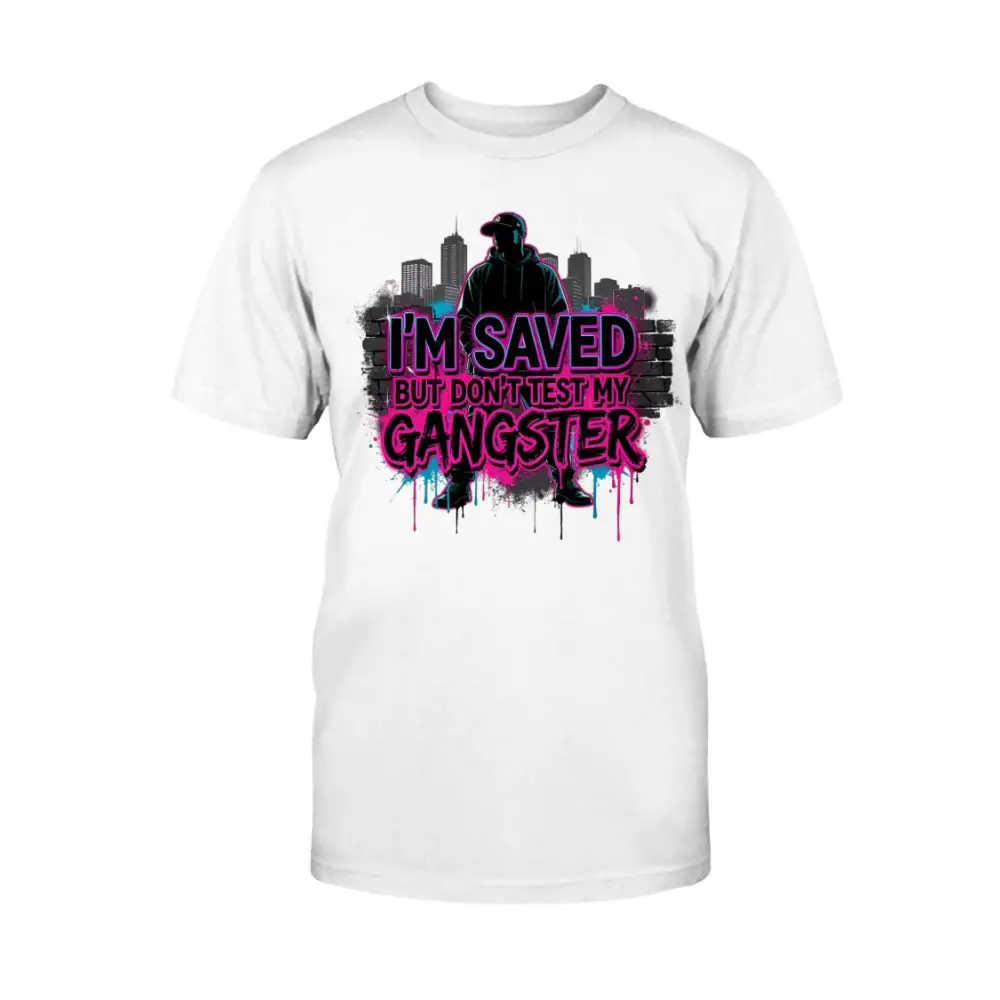 I’m Saved But Don’t Test My Gangster graphic t-shirt featuring bold pink graffiti lettering, urban skyline background, and streetwear silhouette design on white tee.