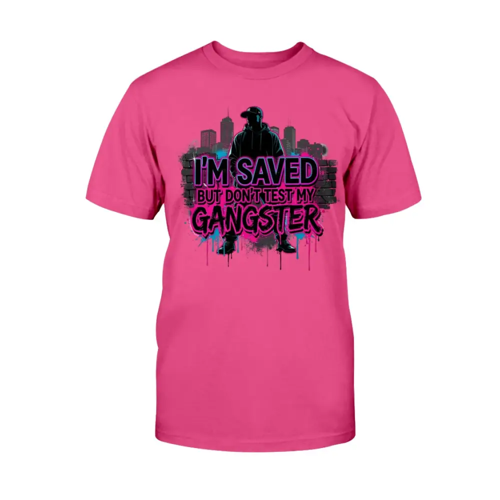 I’m Saved But Don’t Test My Gangster graphic t-shirt featuring bold pink graffiti lettering, urban skyline background, and streetwear silhouette design on hot pink tee.