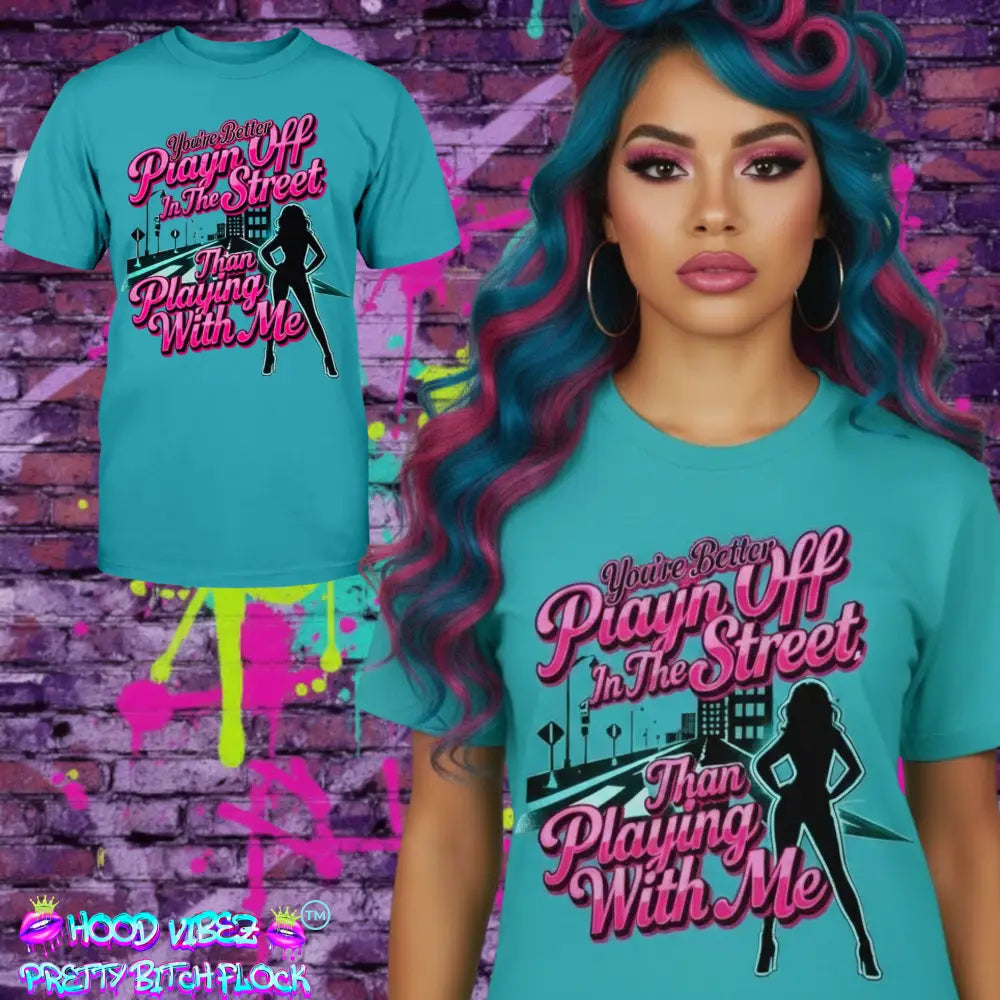 Model wearing Teal graphic t-shirt featuring bold pink statement text “You’re Better Playin’ In The Street Than Playing With Me” with urban city background and female silhouette design by Hood Vibez Pretty Bitch Flock.
