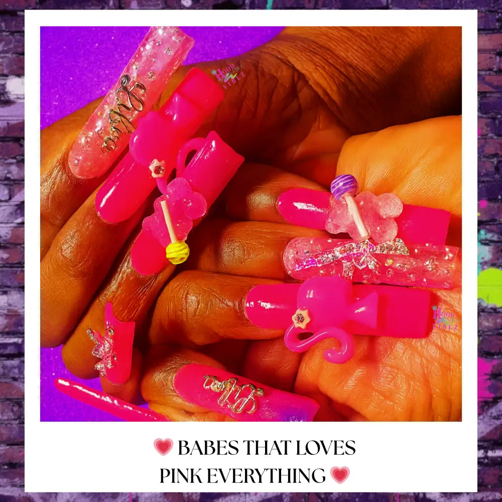 “Close-up of Pink Candy Pop Press-On Nails with 3D candy charms, bows, lollipop accents, and glossy hot pink finish against a purple glitter background.”