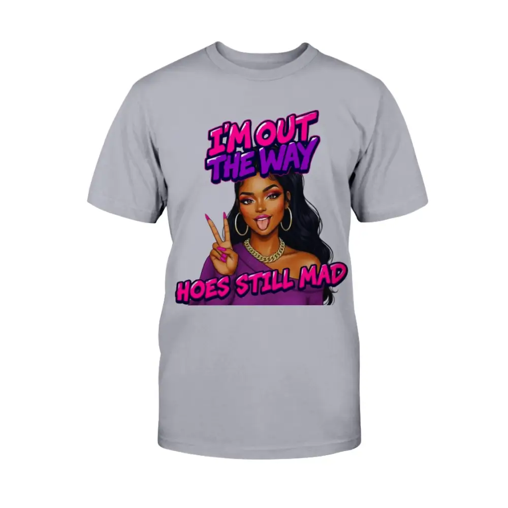 A gray t-shirt featuring a cartoon-style Black woman with long hair, hoop earrings, gold chain, and pink nails flashing a peace sign, with bold pink and purple text that reads “I’m Out the Way, Hoes Still Mad.”"