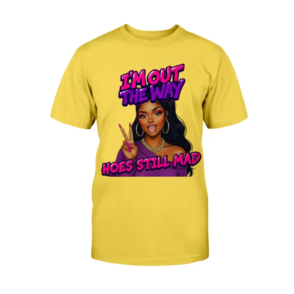 A yellow t-shirt featuring a cartoon-style Black woman with long hair, hoop earrings, gold chain, and pink nails flashing a peace sign, with bold pink and purple text that reads “I’m Out the Way, Hoes Still Mad.”"